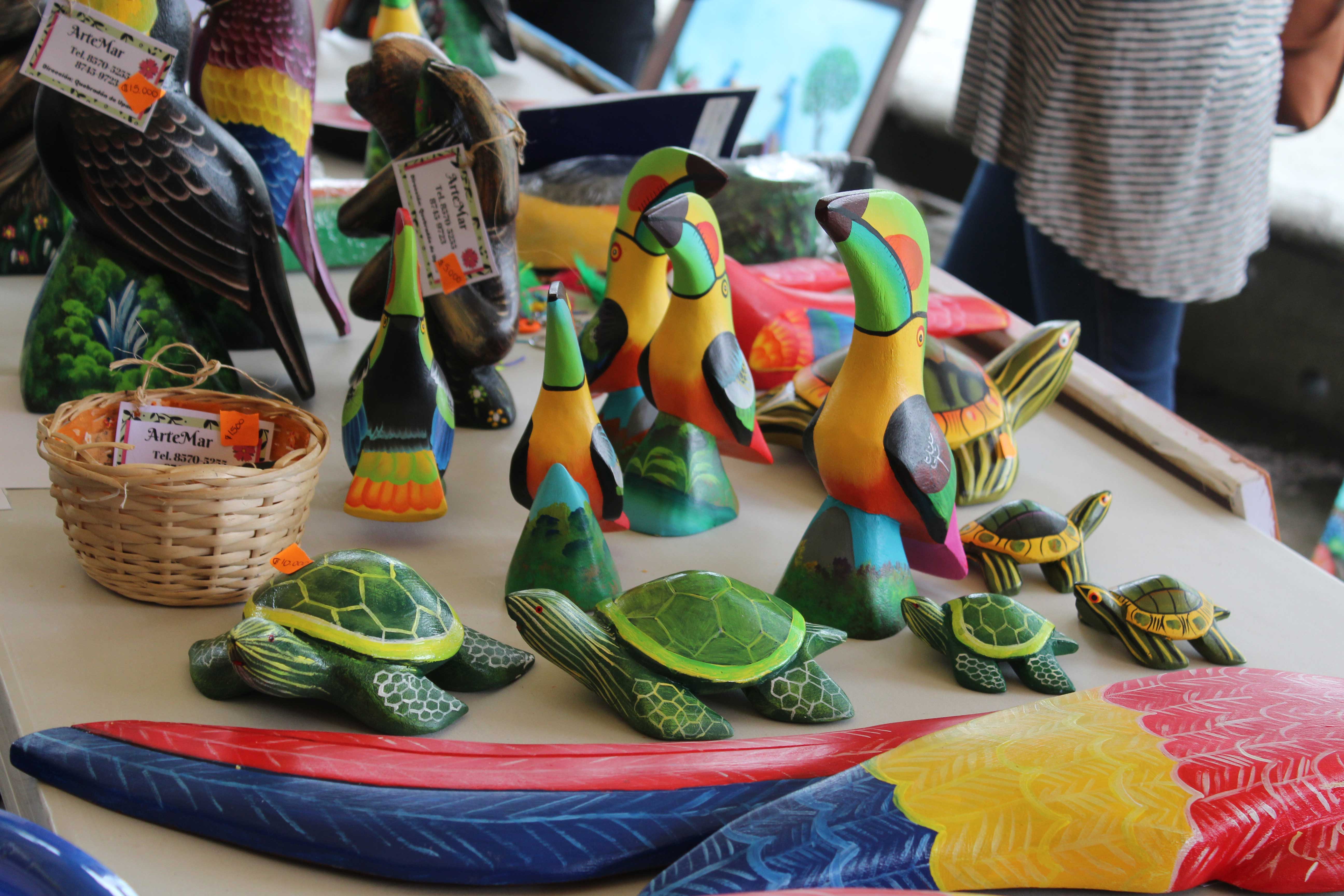 img-galeria-quote-Distintas piezas basadas en animales costarricenses pintadas de colores brillantes, algunos de estos siendo los tucanes y tortugas.