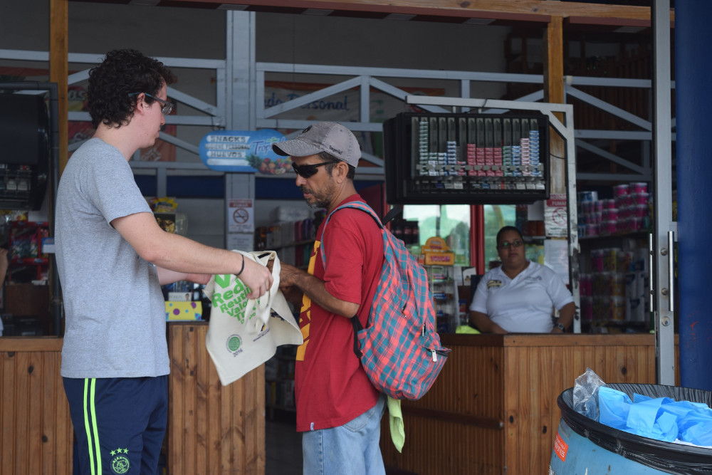 Estudiante y vecino de la comunidad conversan sobre el uso de las bolsas plásticas y los beneficios de las bolsas de tela.  Foto por: Roberto Puello Padilla.