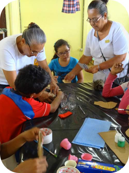 Mujeres de la comunidad de San Felipe de Alajuelita enseñan a niños y niñas cómo realizar un títere.