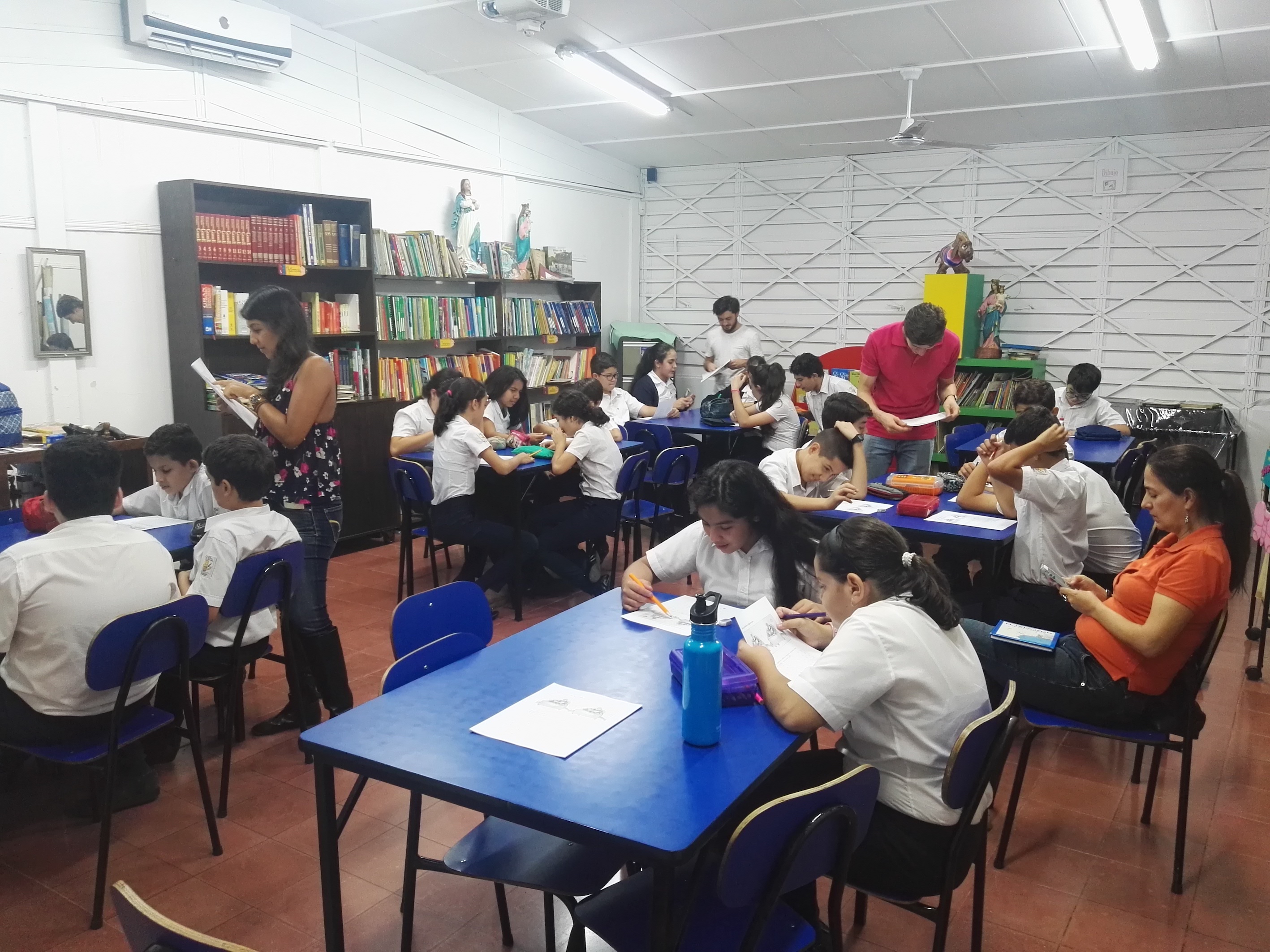 Grupos de estudiantes trabajando en diferentes mesas de la clase. 