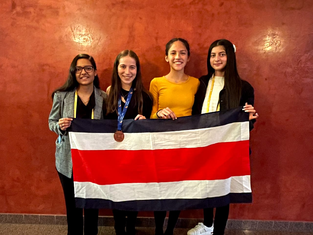 img-noticia-El equipo de jóvenes matemáticas sostiene una bandera de Costa Rica posterior a la premiación del evento mostrando la medalla.